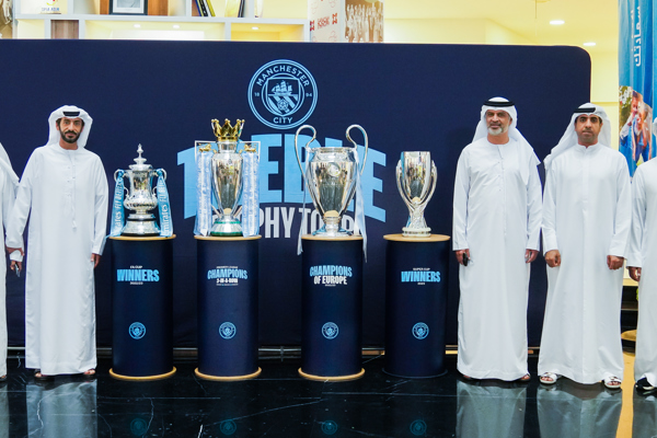 Abu Dhabi Sports Council employees celebrate Manchester City's trophies at their headquarters in Abu Dhabi
